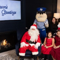 Fmaily dressed in red and little girl looking away from Santa